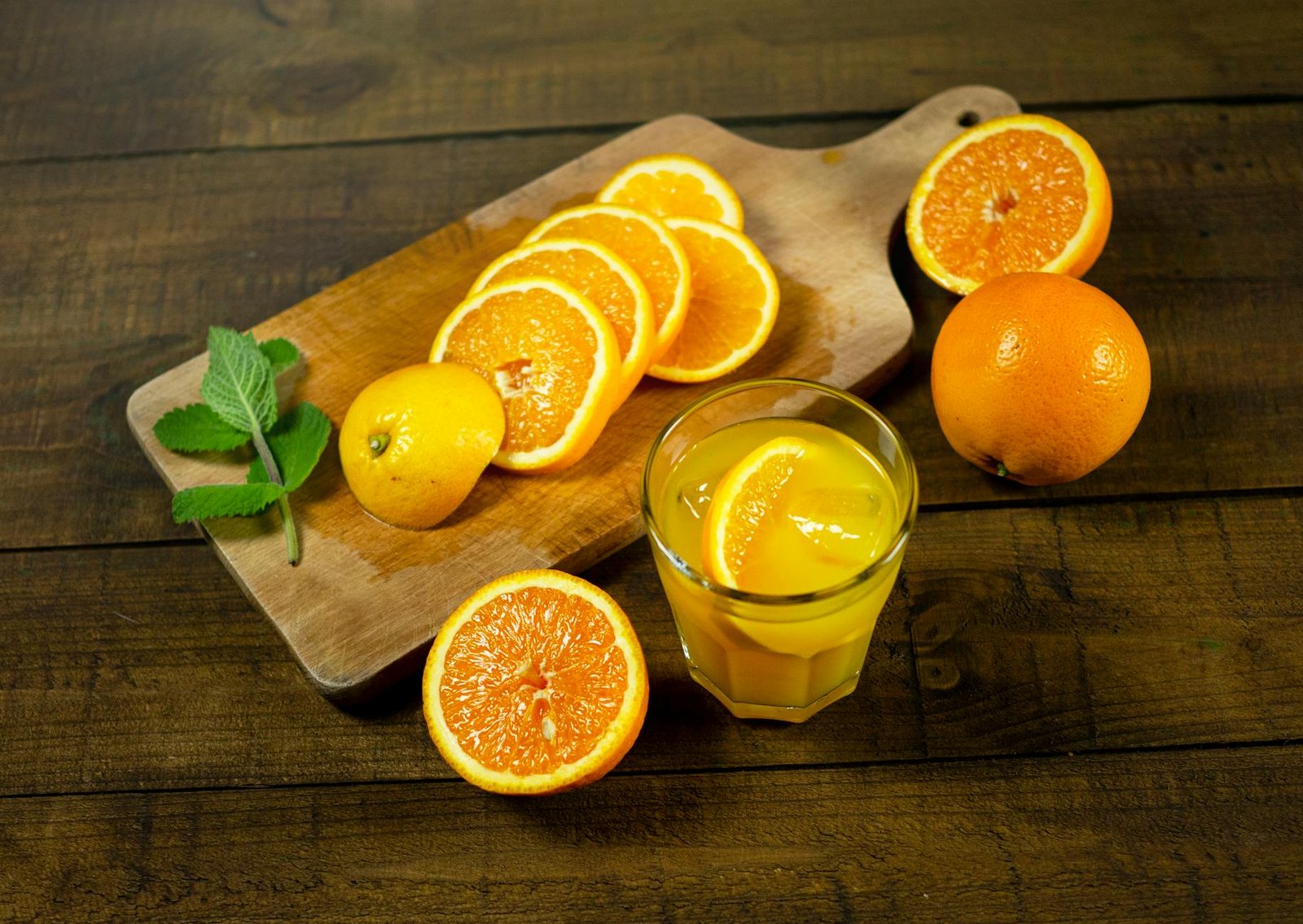 close up photo of slices of orange near a glass with orange juice